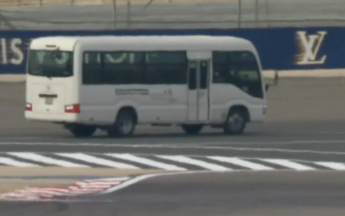 The white bus drives alongside the track