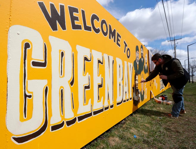 Artist Zane Statz on April 19 paints the Packers fence at 1267 Shadow Lane for the 2025 NFL Draft in Green Bay.